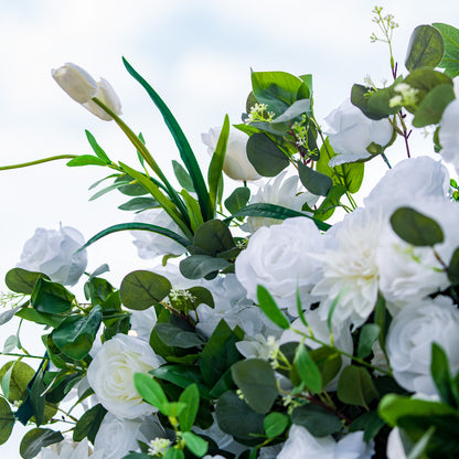 This photo showcases a lush arrangement of white roses, tulips, and other white blooms, set against rich green foliage. The flowers create a serene and elegant display. Ideal for events like a “Pure Bliss” wedding or a refined garden reception, it exudes a sense of purity and sophistication, perfect for upscale and graceful gatherings. 