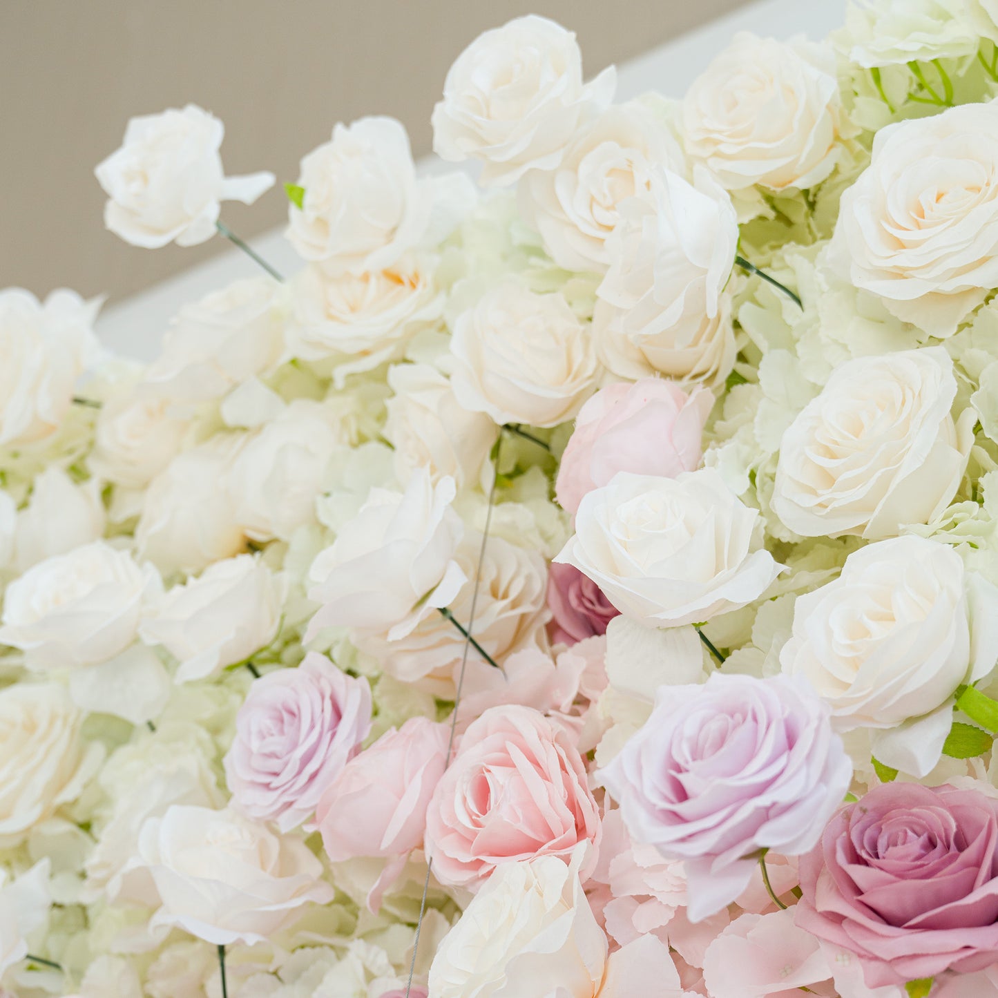 A lush arrangement of white roses, interspersed with soft pink and lavender blooms. The pastel color theme creates a romantic, elegant vibe—perfect for weddings, bridal events, or sophisticated celebrations. The dense, layered flowers offer a dreamy, polished aesthetic, ideal as a decorative backdrop or centerpiece. 