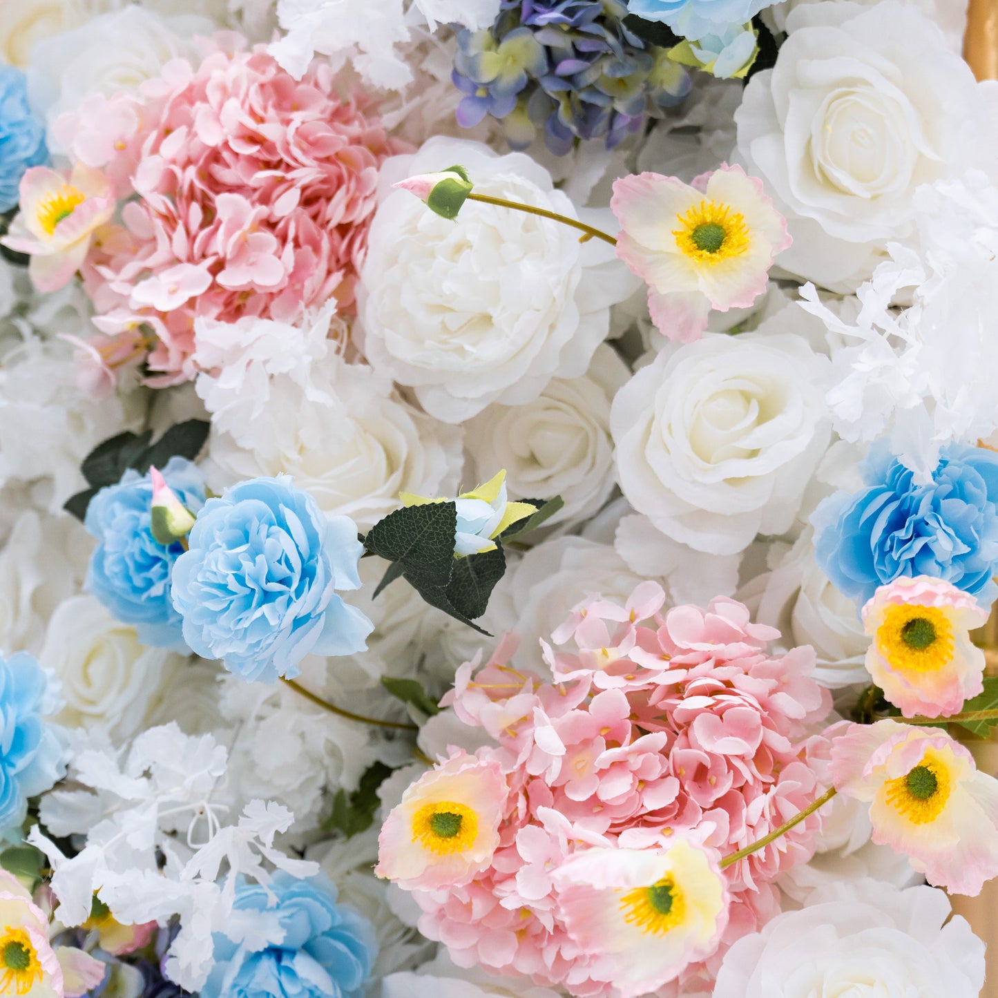 This photo presents a dense arrangement of artificial flowers, with white and blue roses, and pink and blue hydrangeas. It's a vibrant display, perfect for weddings, photo shoots, or other special events, adding sophistication and natural beauty to any setting.
