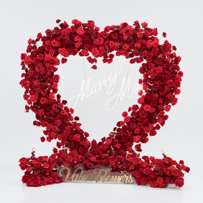 A heart - shaped floral display crafted from dense red roses. At its center, a “Marry Me” sign glows, and the base features a “Valar Flowers” plaque. The vibrant, romantic arrangement is perfect for proposals, blending beauty and sentiment to create a memorable moment. 