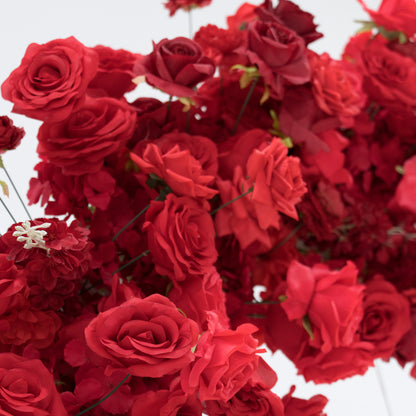 A dense cluster of artificial red roses, showcasing various shades from bright to deep crimson. The blooms, with their velvety petals and green stems, create a lush, romantic arrangement. Perfect for decorative purposes, adding a touch of elegance and passion to any setting. 