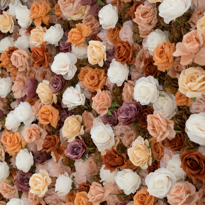 A close - up of a gold “ValarFlowers” sign against a lush artificial flower wall. The wall features beige, white, peach, and purple roses, creating a textured, elegant backdrop. The sign adds a branding element to the decorative floral display. 