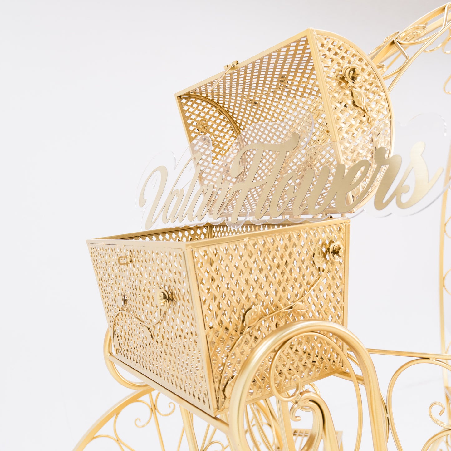 A close - up of a gold, ornate metal trunk with latticework, part of a Cinderella - style carriage. The lid is open, revealing a clear acrylic “ValarFlowers” sign inside. Decorative floral motifs and clasps enhance its fairy - tale charm, perfect for themed displays. 