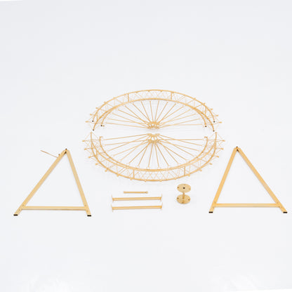 Unassembled parts of a golden Ferris wheel decoration. Includes a circular frame with spokes, two triangular stands, and small metal components. Designed for easy assembly, perfect for decorative, themed event setups.