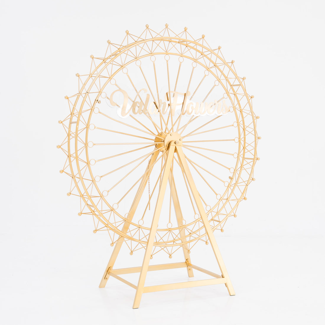 A golden, metal Ferris wheel decoration with a triangular stand. It features intricate spokes and small spheres along the rim. In the center, a stylish, cursive “ValarFlowers” sign adds branding. Ideal for decorative, themed event setups.