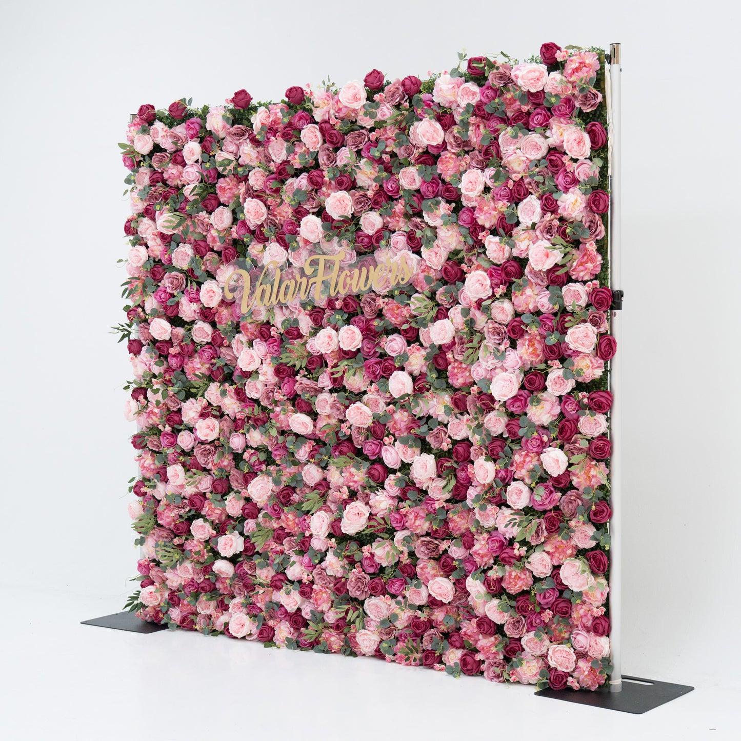 A large artificial flower wall, densely packed with pink and deep - pink roses, plus green foliage. A gold “ValarFlowers” sign is centered, creating an elegant, romantic backdrop—ideal for events, exuding charm and sophistication. 