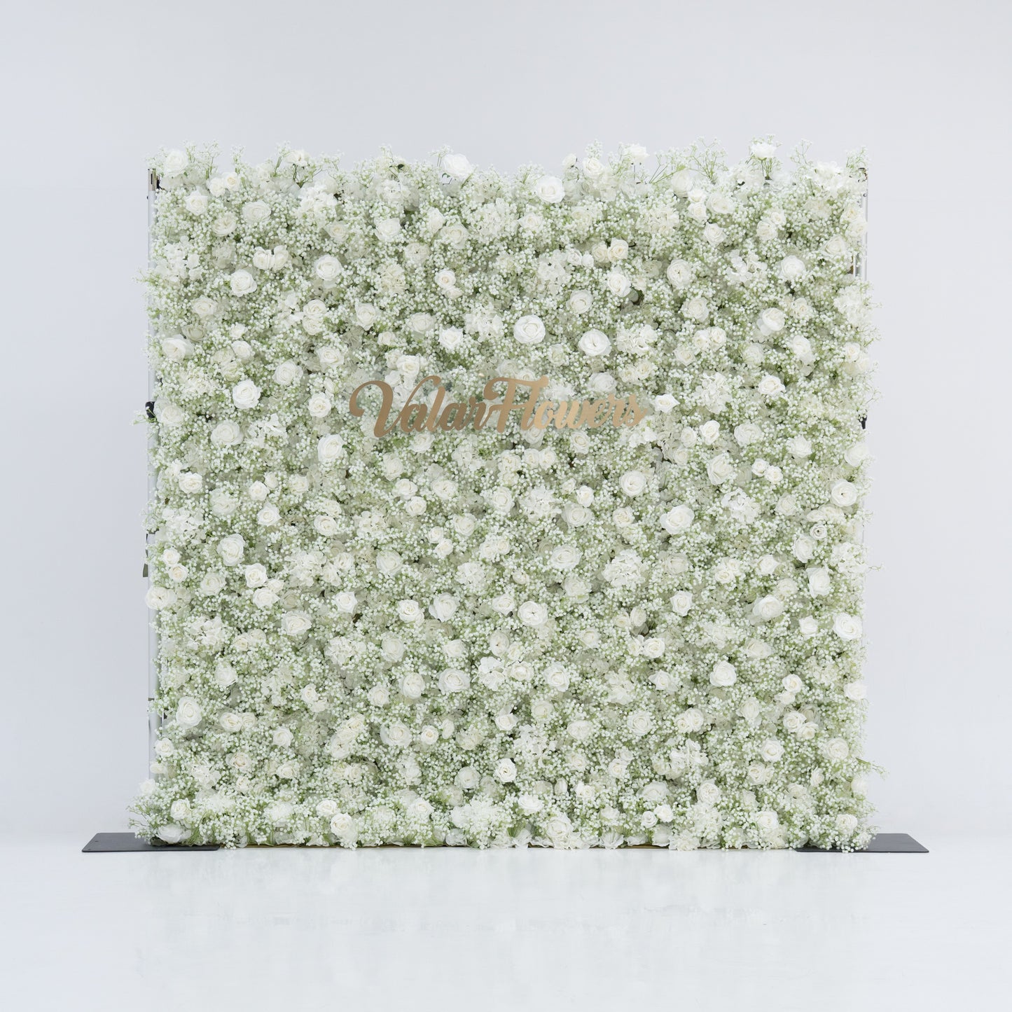 This image showcases a large, square floral wall densely covered with white flowers, including baby's breath and small blooms. "Valar Flowers" is displayed in elegant golden text. Set against a plain white background, the wall exudes a pure, elegant, and refined atmosphere, perfect for decorative purposes in events or as a stylish backdrop, highlighting the beauty of natural flowers.