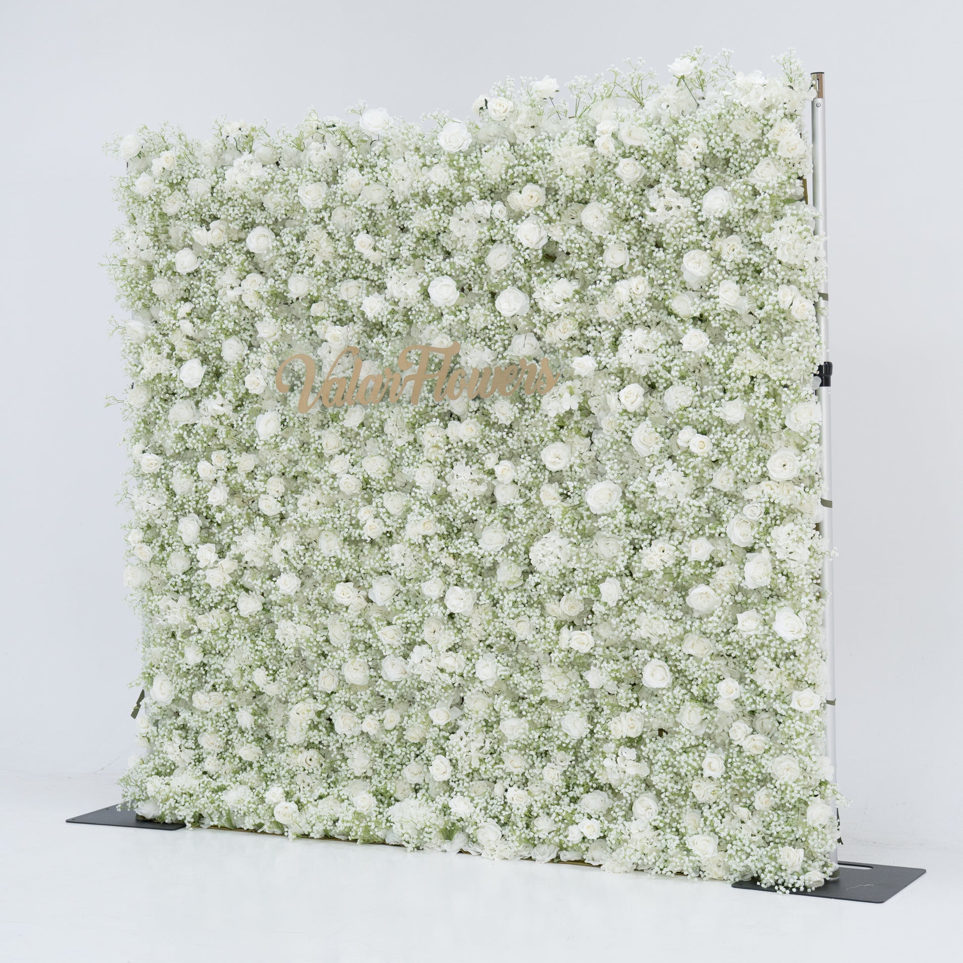 This image showcases a stunning 8x8ft floral wall from Valar Flowers, densely adorned with white flowers, including baby's breath and small blooms. "Valar Flowers" is elegantly displayed in golden text. Set against a plain white background, the wall exudes a pure, elegant, and refined atmosphere, perfect for decorative use in events or as a stylish backdrop, highlighting the brand's craftsmanship and the beauty of the floral arrangement.