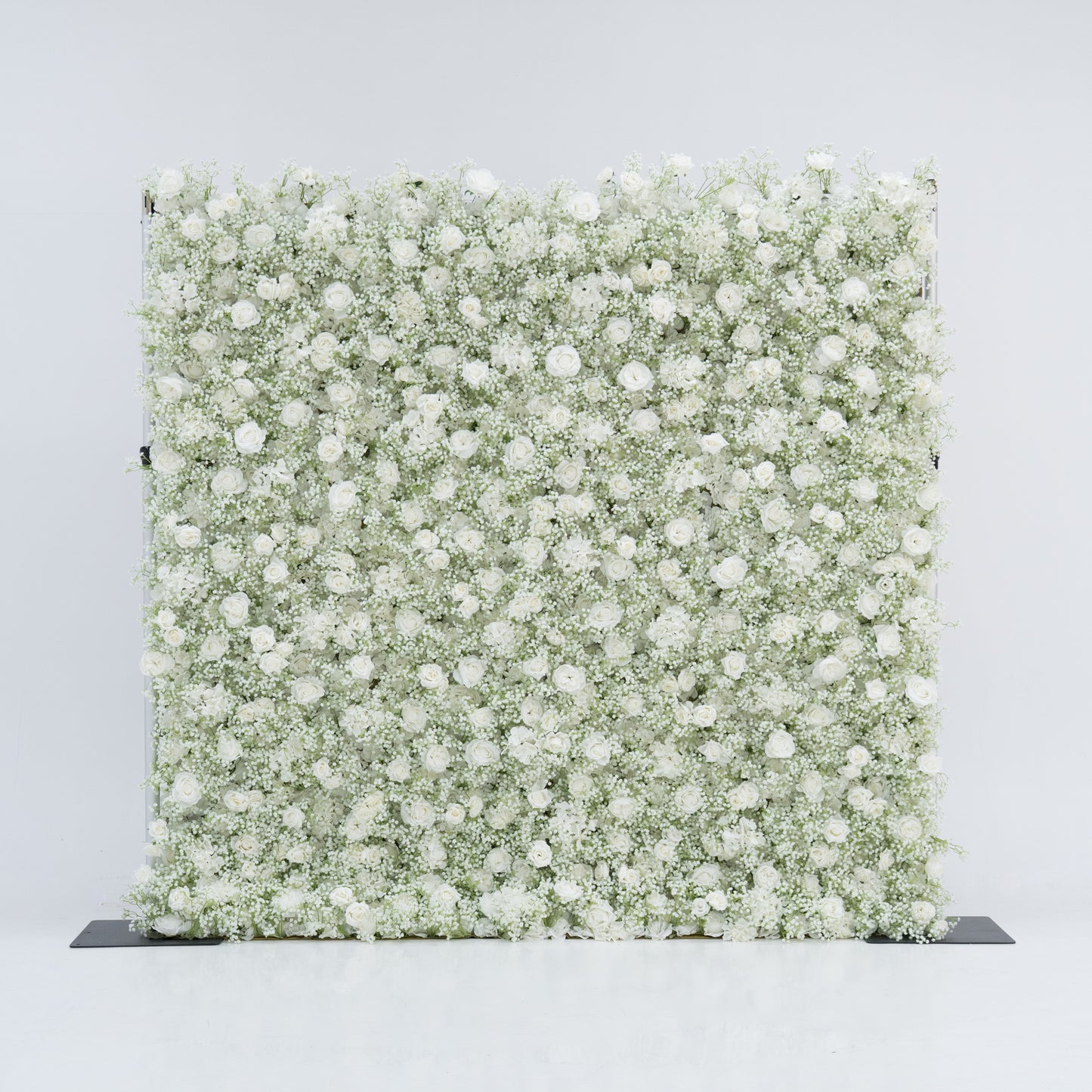 This image features a large, square floral wall densely covered with white flowers, including baby's breath and small blooms. Set against a plain white background, the wall exudes a pure, elegant, and refined atmosphere. It serves as a stunning decorative piece, perfect for events or as a stylish backdrop, highlighting the beauty and intricacy of the floral arrangement.