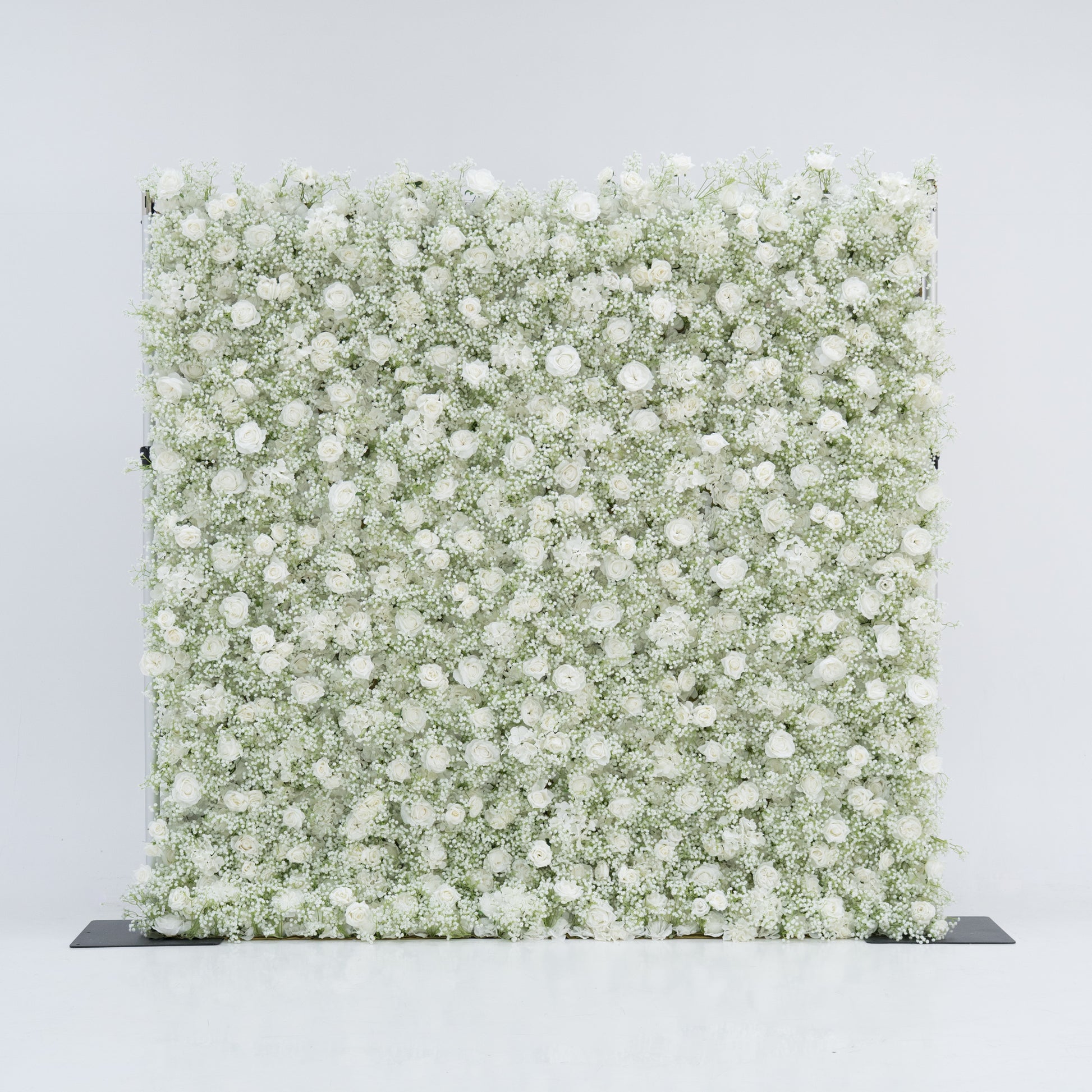 This image features a large, square floral wall densely covered with white flowers, including baby's breath and small blooms. Set against a plain white background, the wall exudes a pure, elegant, and refined atmosphere. It serves as a stunning decorative piece, perfect for events or as a stylish backdrop, highlighting the beauty and intricacy of the floral arrangement.