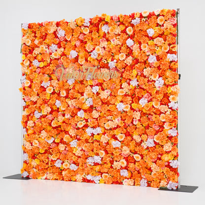 This image showcases a vibrant floral backdrop by Valar Flowers, featuring a dense arrangement of artificial flowers in warm shades of orange, peach, red, and hints of pink and purple. The textured display exudes energy, with the brand’s name elegantly integrated in gold. Set against a plain white indoor background, it’s perfect for adding a bold, nature-inspired element to events or interiors, highlighting Valar Flowers’ craftsmanship in eye-catching, sophisticated decor.