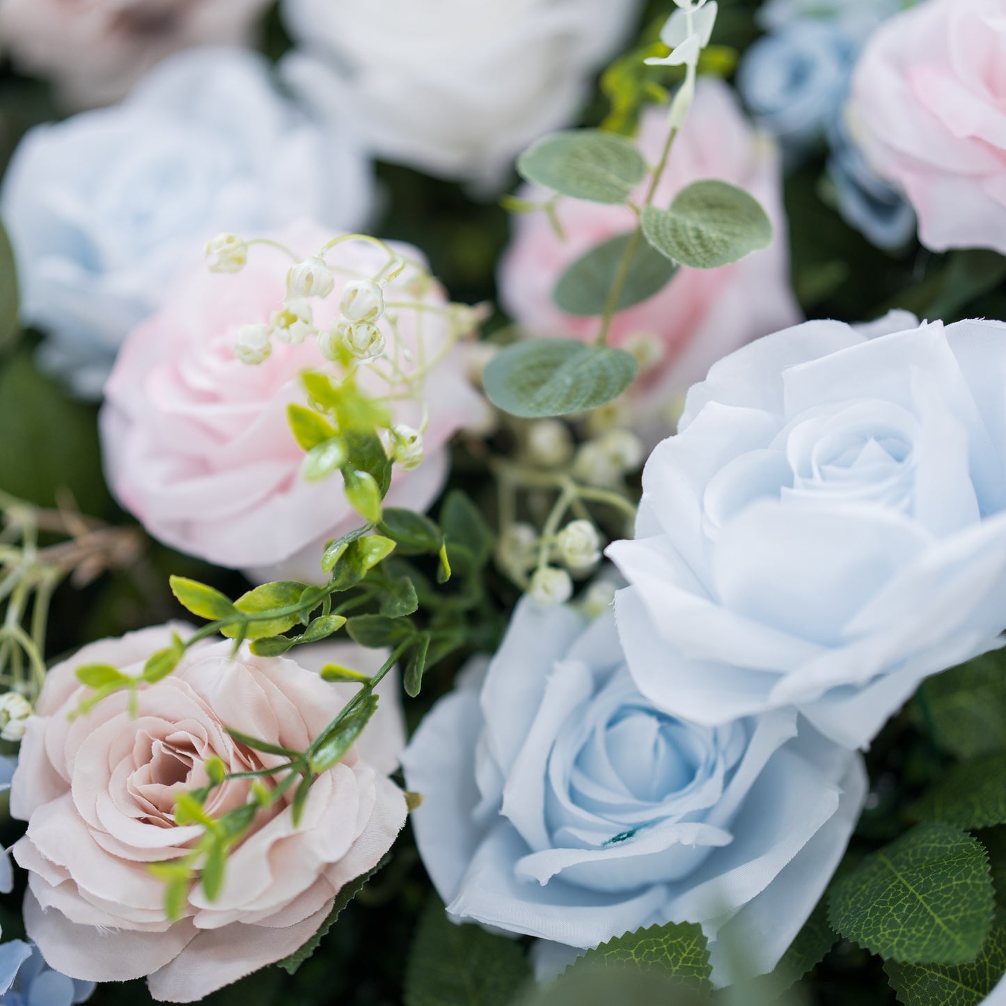 This image showcases a vibrant section of a floral backdrop by Valar Flowers, featuring a dense arrangement of artificial flowers in shades of light blue, pink, blush, and white. Complemented by green foliage and delicate accents like baby’s breath, it exudes elegance and is perfect for adding a sophisticated, nature-inspired element to events, highlighting Valar Flowers’ craftsmanship in detailed, eye-catching decor.