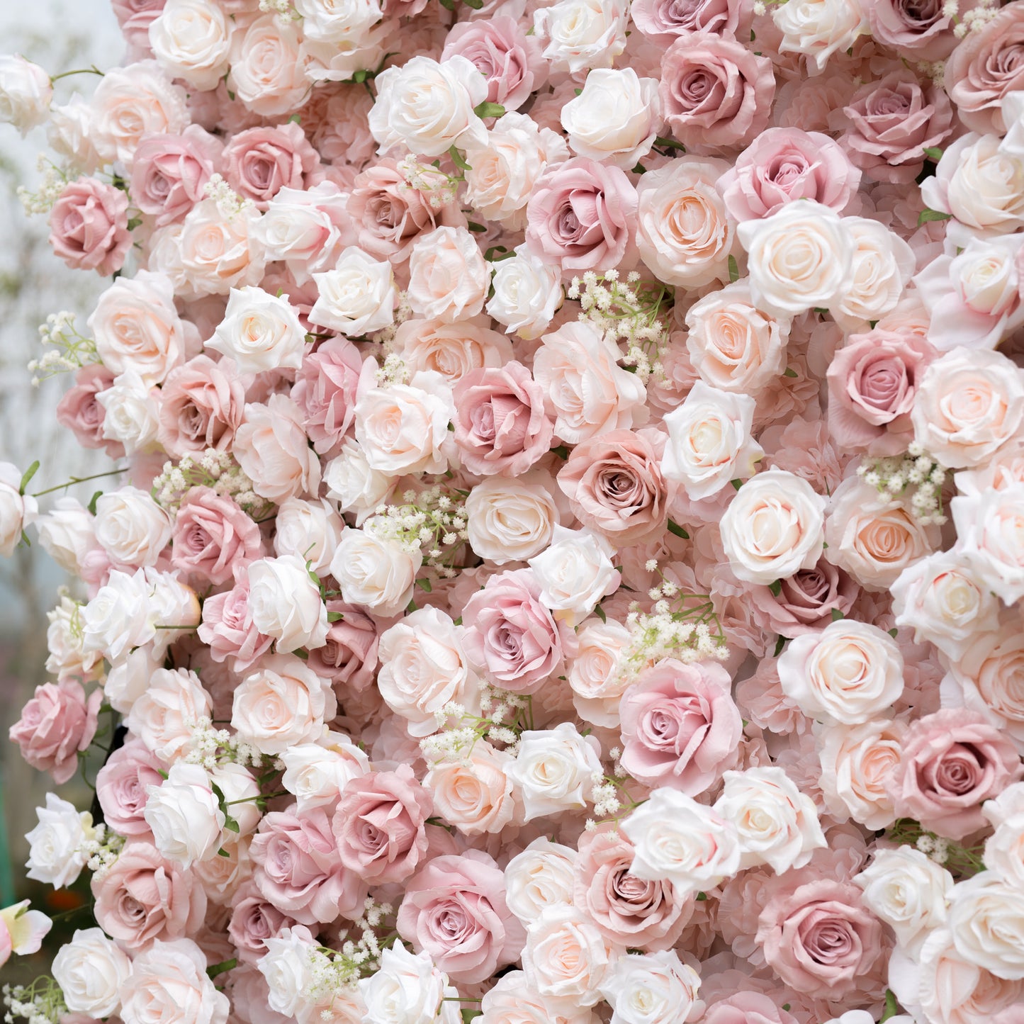 A lush close-up of a Valar Flowers floral wall featuring a romantic mix of blush, dusty rose, and creamy white roses, accented with delicate baby's breath. The dense, layered blooms create a soft, elegant texture, perfect for luxury wedding backdrops and romantic event decor.