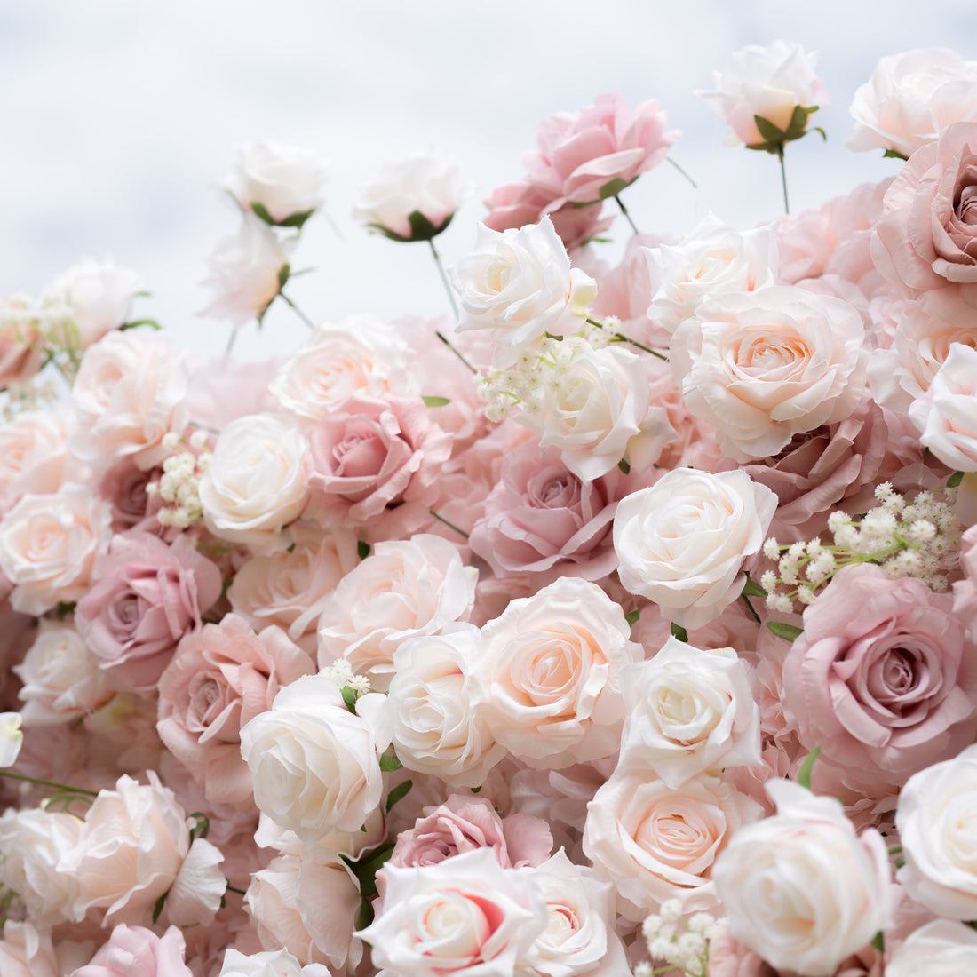 A close-up of a Valar Flowers floral arrangement, showcasing a lush, romantic blend of creamy white, soft blush, and dusty pink roses, interspersed with delicate baby&