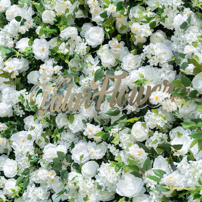This close-up showcases Valar Flowers’ premium all-white artificial flower wall, featuring lush, hyper-realistic roses, peonies, and delicate filler blooms paired with vibrant green foliage. Centered with a metallic "ValarFlowers" logo, the dense, layered design highlights lifelike petals and soft textures, creating an elegant, maintenance-free display. Ideal for weddings, photo booths, and luxury events, this durable decor offers a clean, romantic aesthetic perfect for professional styling.