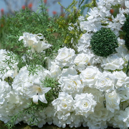 This close-up showcases Valar Flowers’ premium artificial floral arrangement, featuring lush white roses, hydrangeas, lilies, and delicate green foliage, including a spherical green accent. The dense, realistic blooms mimic fresh flowers, with soft petals and lifelike textures creating an elegant, romantic aesthetic. Maintenance-free and durable, this display is ideal for weddings, photo booths, and luxury events, offering a clean, timeless look perfect for professional styling.