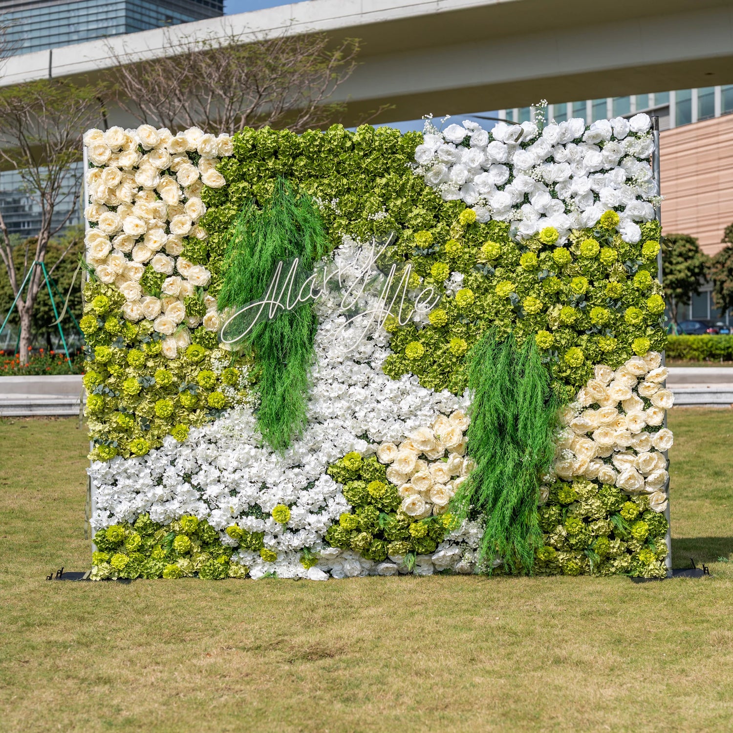 This is a stunning 10x8ft artificial flower wall backdrop by Valar Flowers, featuring a lush, nature-inspired design with vibrant green hydrangeas, cascading foliage, soft ivory roses, and crisp white blooms. Centered with a custom "Marry Me" neon sign, this reusable, maintenance-free display creates a romantic focal point, ideal for outdoor weddings, proposals, photo booths, and luxury events, offering long-lasting beauty for professional decor.