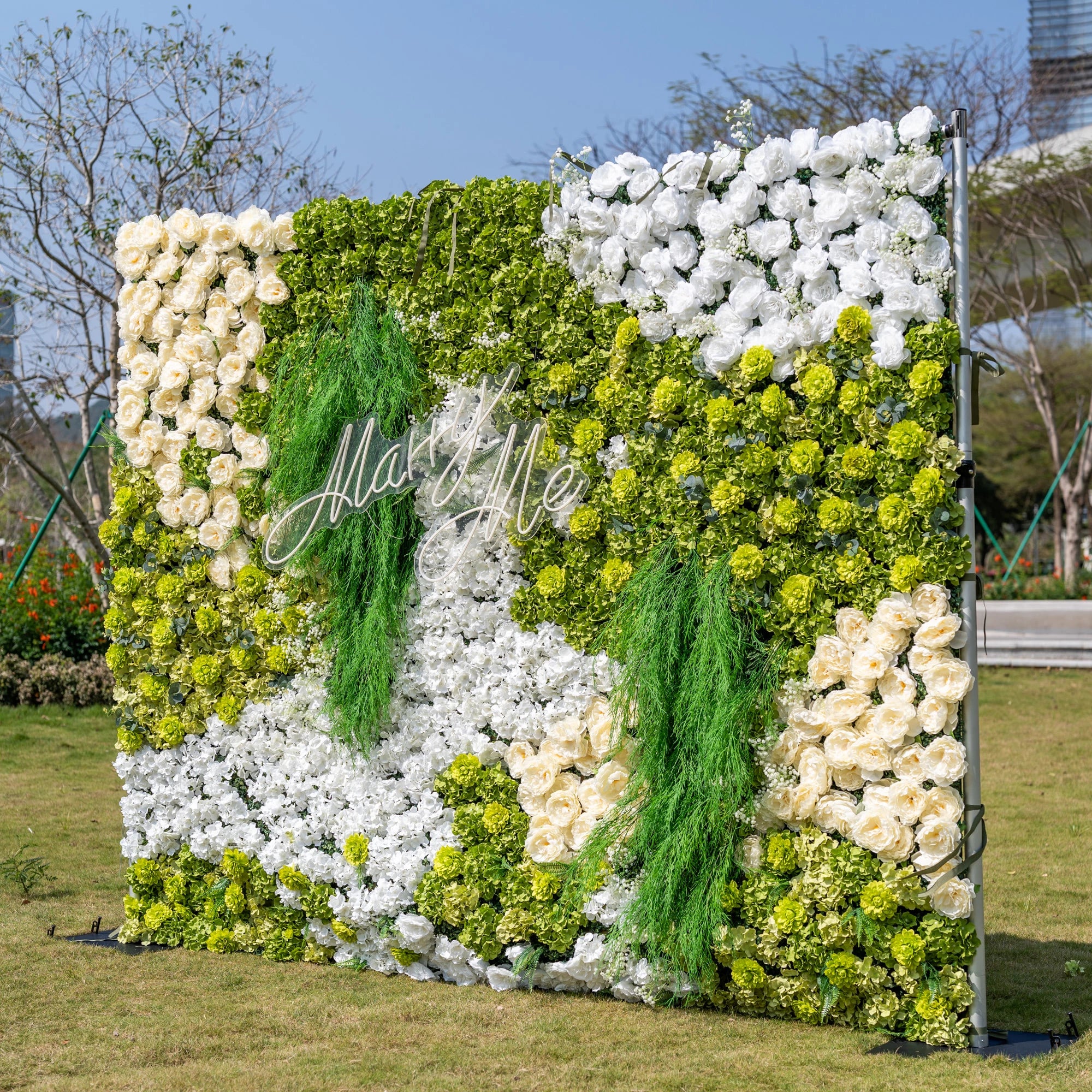 This is a stunning 10x8ft artificial flower wall backdrop by Valar Flowers, featuring a lush, nature-inspired design with vibrant green hydrangeas, cascading foliage, soft ivory roses, and crisp white blooms. Centered with a custom "Marry Me" neon sign, this reusable, maintenance-free display creates a romantic focal point, ideal for outdoor weddings, proposals, photo booths, and luxury events, offering long-lasting beauty for professional decor.