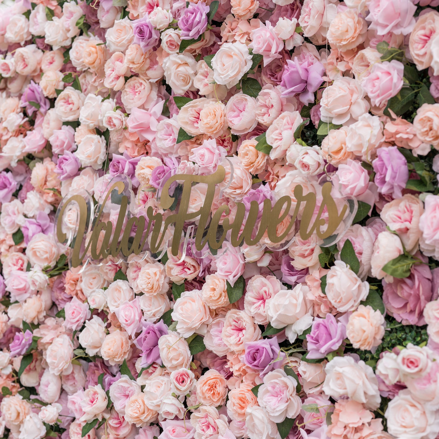 Dreamy close-up of Valar Flowers silk flower wall with blush pink dusty rose peach and lavender roses accented by layered peony blooms in soft romantic blur evoking fine art for bridal portraits and luxury ceremony backdrops