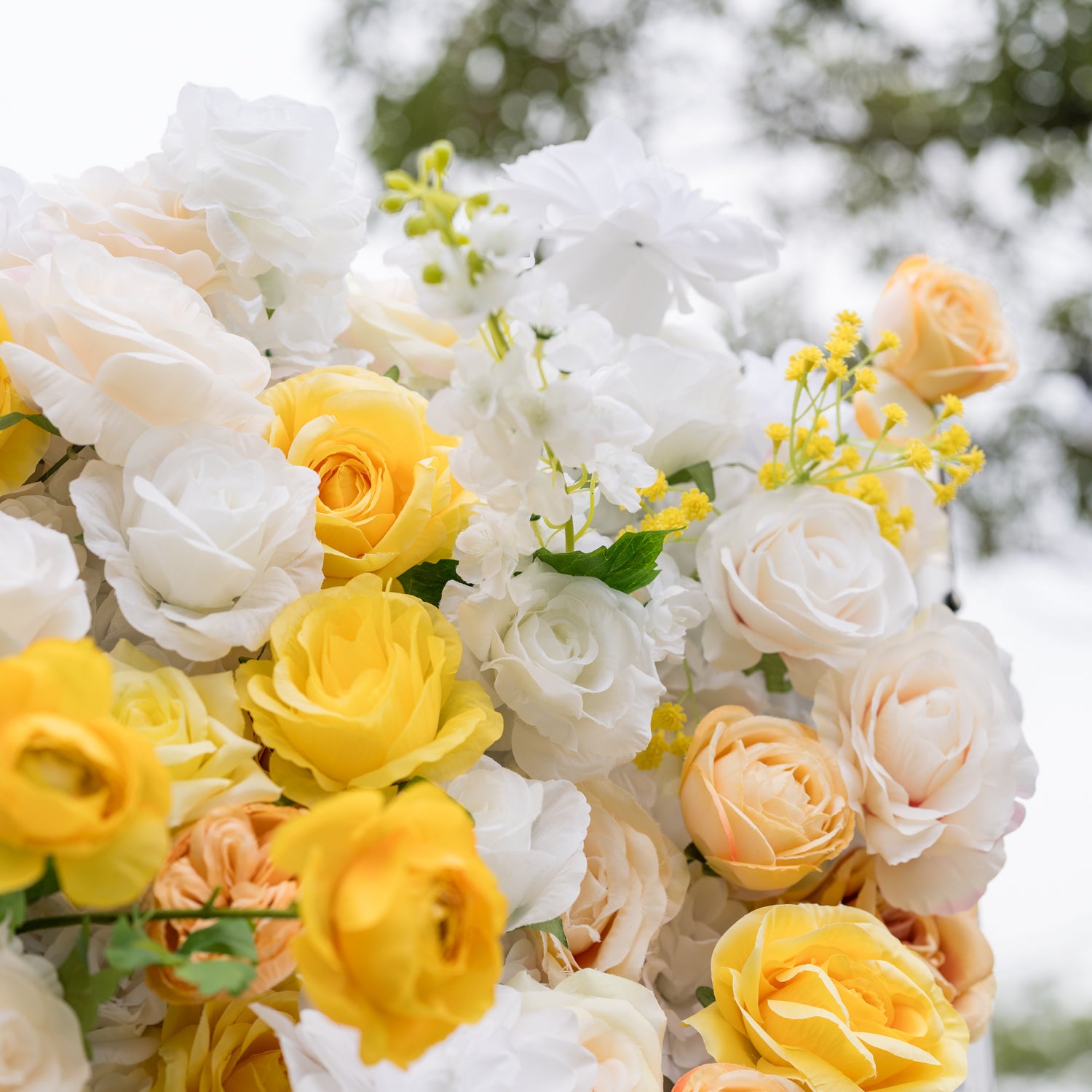 Close-up of Valar Flowers Sun-Kissed Meadow wall: layered white roses, yellow peonies, and peach hydrangeas with soft blurred backdrop. Lush craftsmanship for bridal showers, baby showers, and romantic photo booth settings.