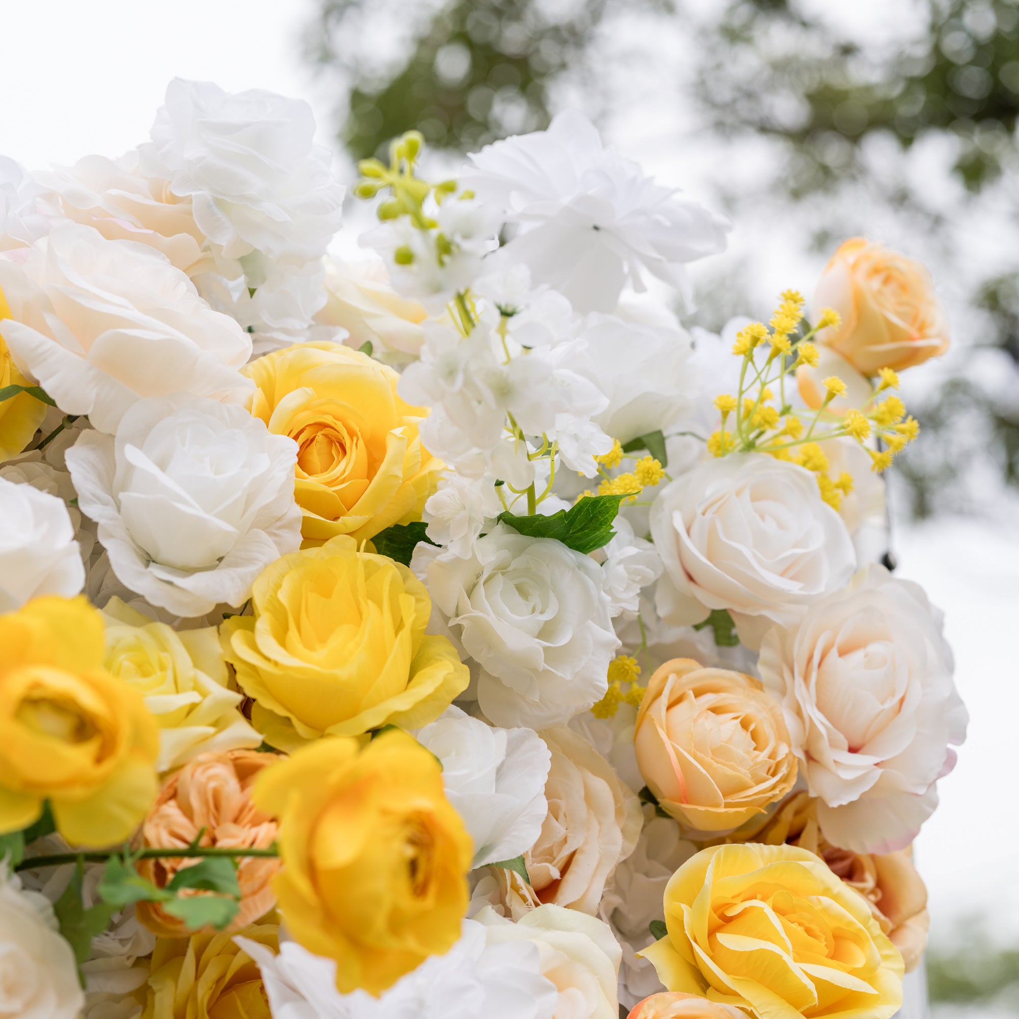 Close-up of Valar Flowers Sun-Kissed Meadow wall: layered white roses, yellow peonies, and peach hydrangeas with soft blurred backdrop. Lush craftsmanship for bridal showers, baby showers, and romantic photo booth settings.