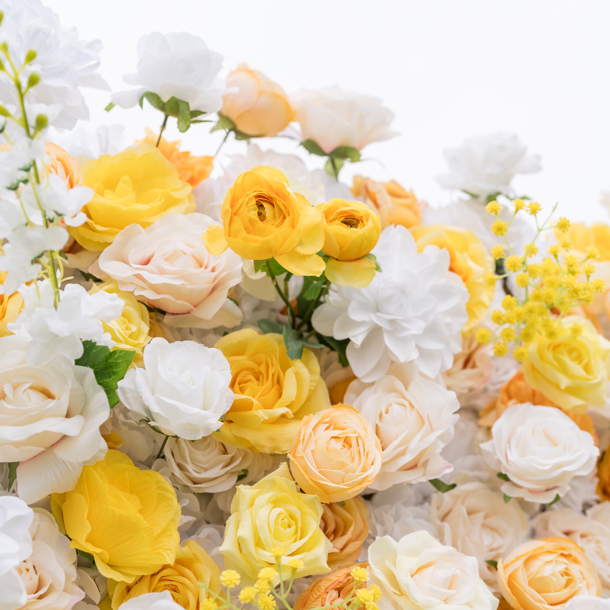 Intimate low-angle close-up of Valar Flowers silk rose ranunculus wall in white, sunny yellow, and warm peach with delicate filler flowers. Bright romance for wedding ceremonies and sweetheart table backdrops.
