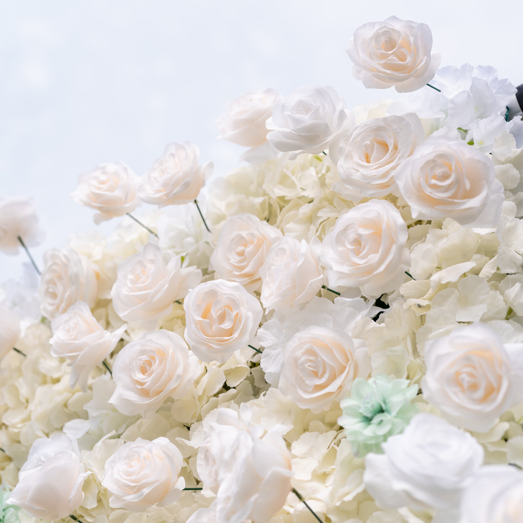 Intimate close-up of Valar Flowers Ethereal Serenity silk rose dahlia and hydrangea wall in dusty blue sage green and creamy white with silver eucalyptus accents bright natural light for gender-neutral baby shower and bridal event backdrops