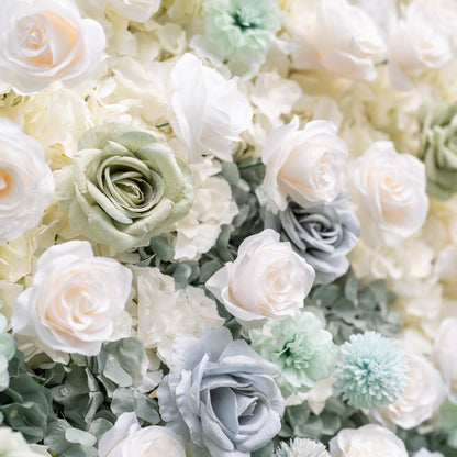 Side-angled close-up of Valar Flowers Ethereal Serenity wall with metallic script sign among steel blue and mint green roses with shallow focus blurring into greenery and sky for sophisticated salon boutique and nursery interior decor installations