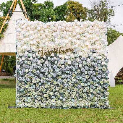 Frontal view of Valar Flowers Ethereal Serenity wall on silver metal frame with dusty blue sage green and ivory roses dahlias and hydrangeas on manicured lawn with teepee canopy blurred behind for sophisticated outdoor wedding receptions and luxury garden galas