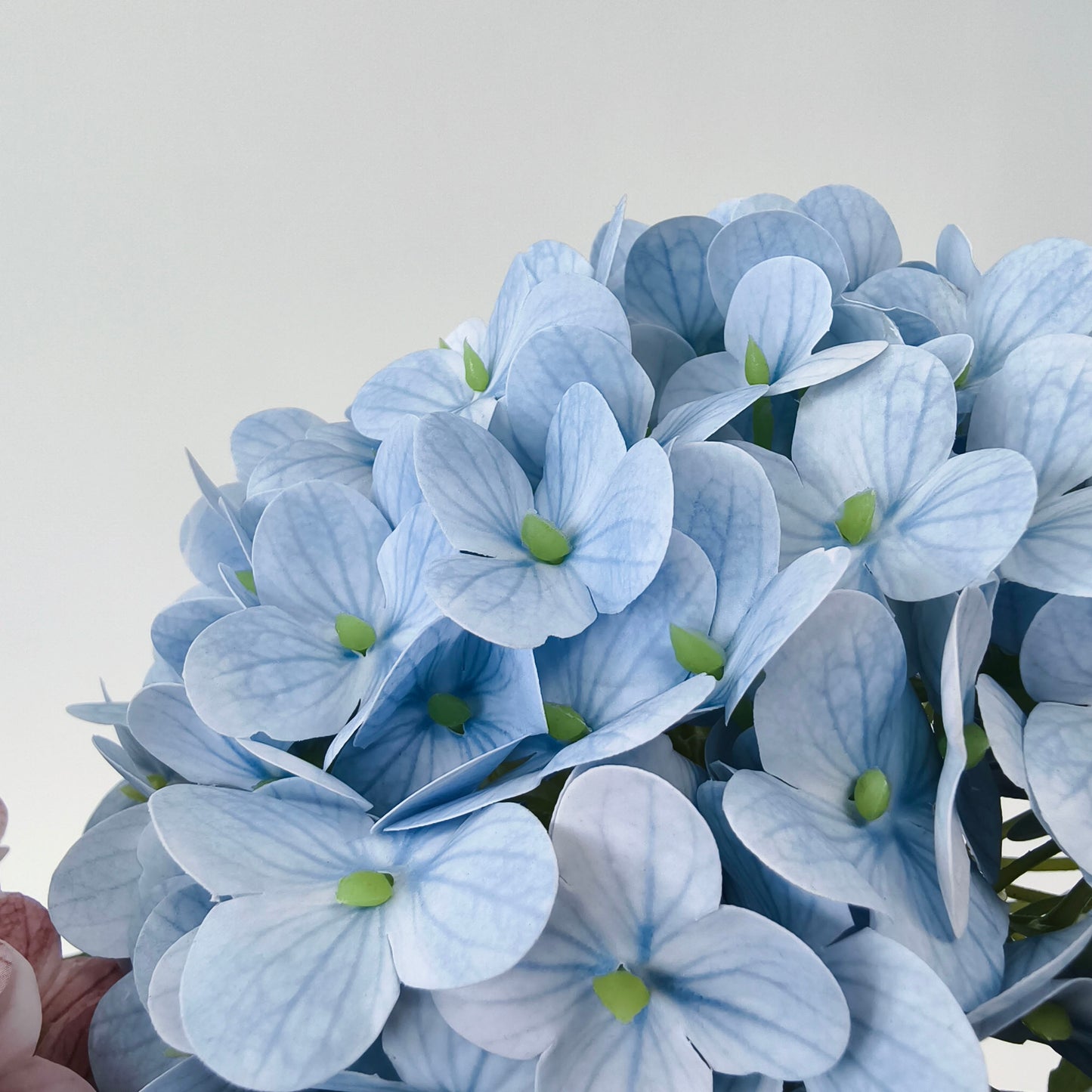 This is a cluster of artificial light - blue hydrangea flowers. The petals have subtle vein patterns and green centers, creating a realistic texture. The dense, rounded blooms offer a soft, delicate aesthetic, ideal for adding a touch of gentle color and charm to home decor or floral arrangements. 