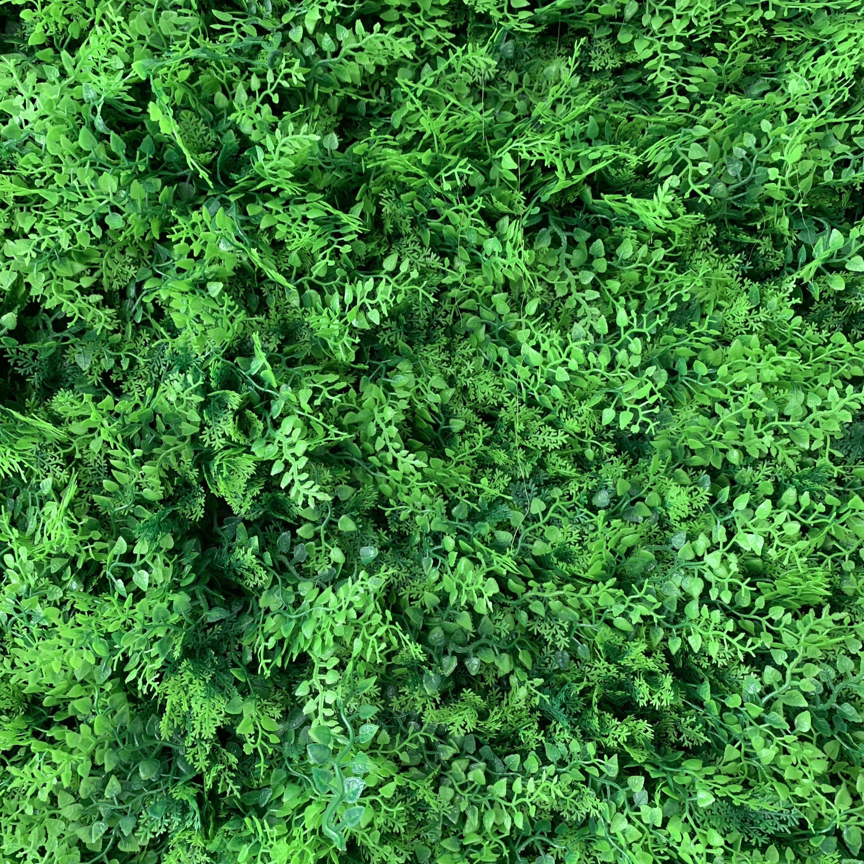 This image showcases a dense, lush expanse of artificial greenery. It features a rich variety of small, textured green leaves and foliage in different shades of green, creating a vibrant, multi-dimensional display. The intricate details and varied plant shapes give it a highly realistic, natural appearance, ideal for use as a backdrop or decor element to bring an organic, refreshing, and serene atmosphere to spaces or events.