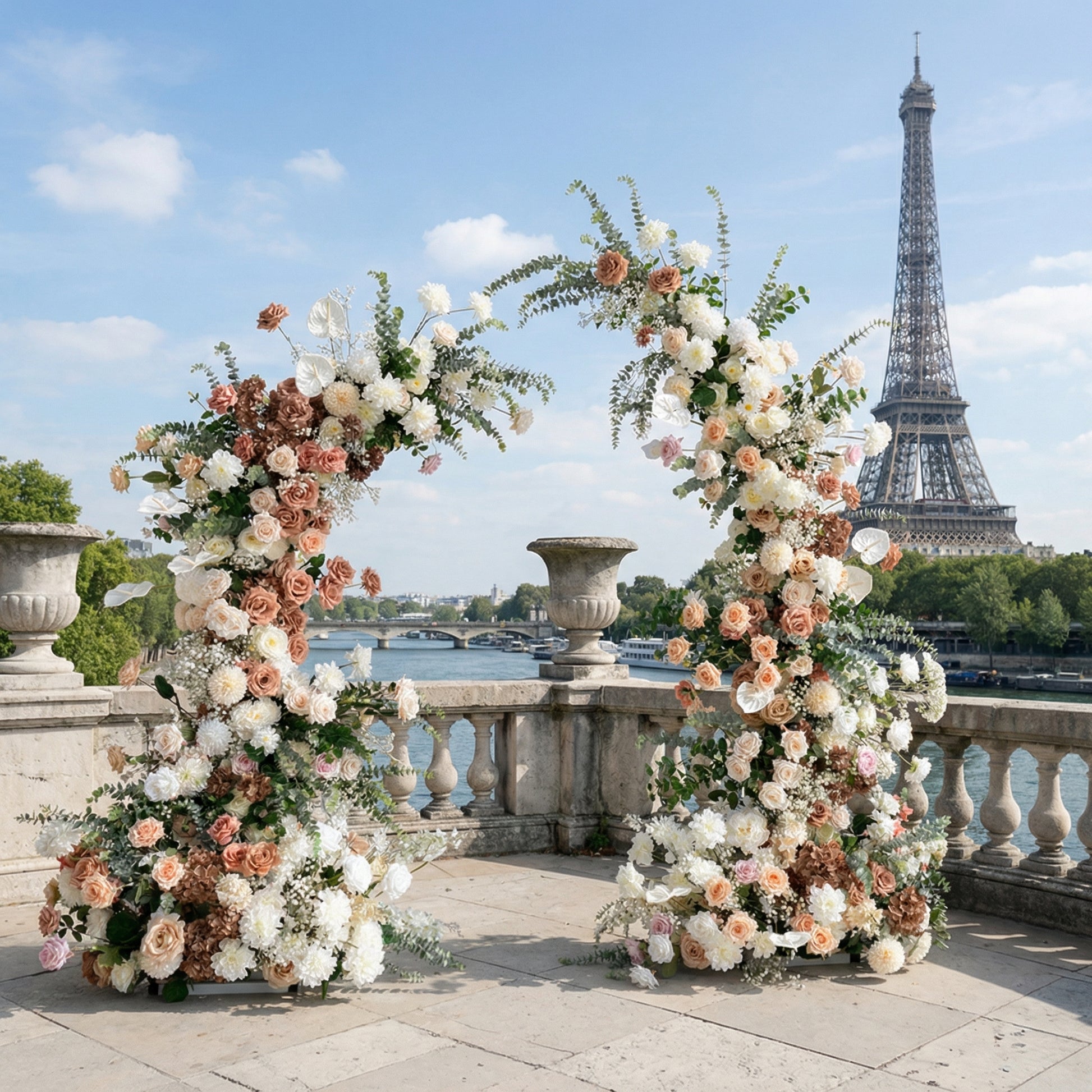 A romantic, asymmetrical floral arch from Valar Flowers, crafted with a soft, warm palette of blush pink, terracotta, and creamy white blooms—including roses, peonies, and delicate baby's breath—intertwined with silvery eucalyptus and lush greenery. Set on a sunlit Parisian riverside terrace with the iconic Eiffel Tower in the background, it creates a dreamy, elegant, and sophisticated atmosphere perfect for luxury weddings and editorial photoshoots.
