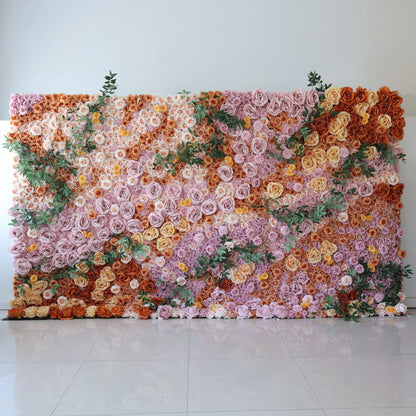 This is a 16x8ft floral wall by Valar Flowers. It features a dense, artful arrangement of artificial flowers in a rich palette—soft pinks, warm oranges, creamy yellows—interspersed with lush green foliage. The flowers create a lush, textured, and visually captivating display, exuding elegance and charm, perfect for adding a touch of sophistication to events or interior spaces.