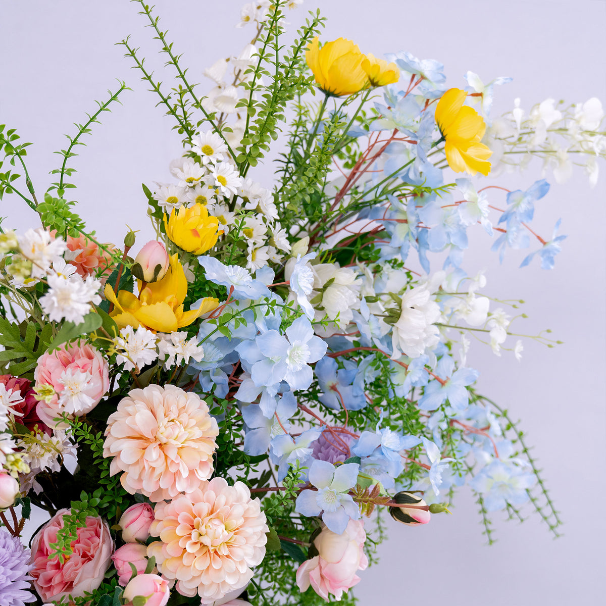 This photo presents a beautiful arrangement of artificial flowers. It includes soft pink roses, peach - toned dahlias, bright yellow blooms, delicate white daisies, and light blue blossoms, all mixed with lush green foliage. The pastel and vibrant hues create a fresh, cheerful vibe, perfect for adding a touch of natural elegance to weddings, events, or home decor. The realistic textures of the faux flowers offer long - lasting beauty, ideal for crafting a charming and polished aesthetic. 