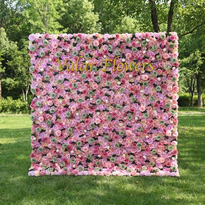 Vibrant mixed pastel artificial flower wall filled with blush, lavender, magenta roses and mint green floral buds, set on a sun-dappled green lawn. Centered glossy golden "Valar Flowers" custom branding highlights the panel. This reusable, zero-maintenance floral backdrop features full dense blooms, ideal for wedding photo booths, bridal showers, boutique decor and colorful pastel social media content shoots for whimsical event styling.