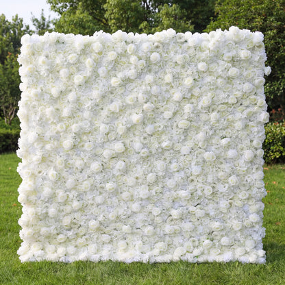 This image showcases a stunning white flower wall by Valar Flowers, composed of dense artificial white roses and blooms. Set outdoors on lush green grass with trees in the background, it exudes elegance and is ideal for events like weddings. The meticulous arrangement highlights Valar Flowers’ craftsmanship in creating sophisticated, eye-catching floral decor.