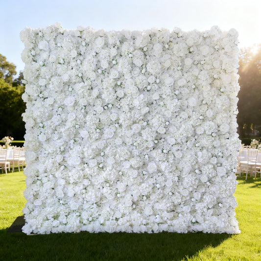 This image showcases a large, square floral wall outdoors on a lush green lawn. It's densely covered with pure white flowers, creating a clean, elegant, and serene display. Bathed in sunlight, with trees and event - like setups (white chairs) in the background, the scene exudes a sense of purity, grace, and natural beauty, perfect for decorative purposes in special events or as a captivating backdrop.