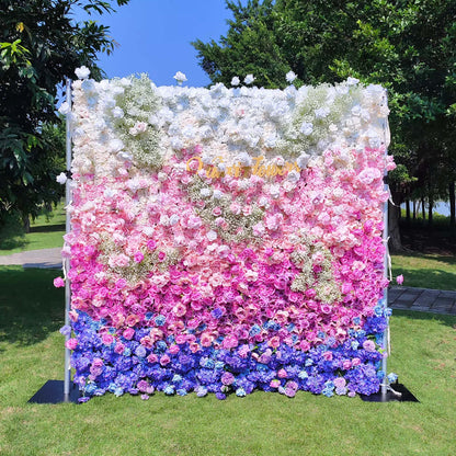 This photo features a lush floral wall with a gradient of white, pink, and blue. Composed of roses and hydrangeas, with baby&