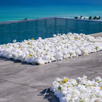 This backdrop features a dense arrangement of artificial white flowers with some golden - hued leaves, set against a stunning ocean - side view with a pool. The white blooms exude purity and elegance.

It&