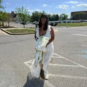 Woman in a white dress holding flower bouquet in a parking lot