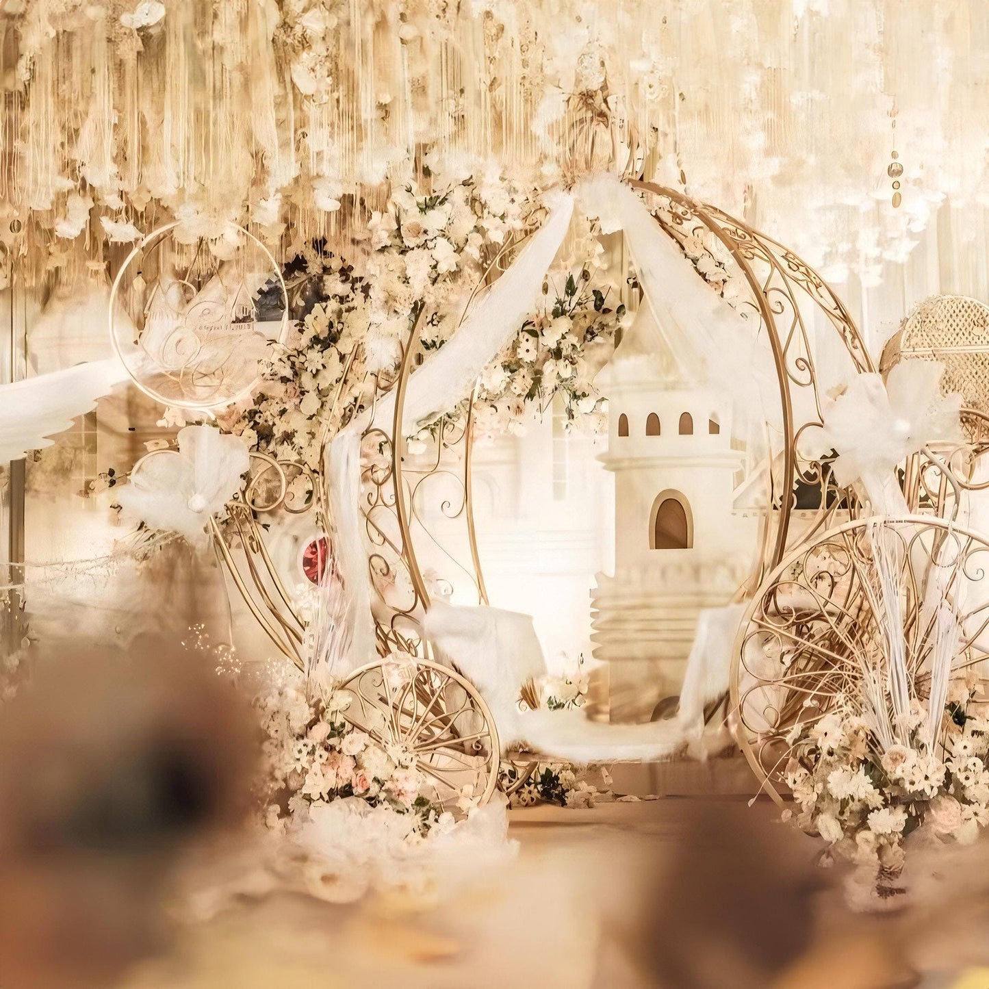 This luxurious event setup by 'ValarFlowers' features an ornate fairytale carriage adorned with elegant floral arrangements, soft drapery, and golden accents, creating a romantic, enchanting atmosphere.