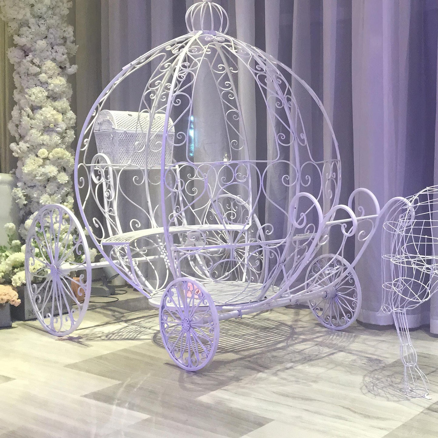 This image by 'ValarFlowers' features a fairytale-inspired white wrought iron carriage with intricate floral designs. It’s ideal for elegant wedding decor, princess-themed events, and unique photo backdrops.
