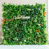 This image features a lush artificial green wall by ValarFlowers. The wall is densely packed with a variety of faux plants, including different shades of green foliage such as ivy - like leaves, ferns, and broad - leafed plants. There are also pops of color from orange and red - tinged plants, adding a vibrant contrast. The overall effect is a rich, natural - looking greenery backdrop, ideal for events or decor purposes. 