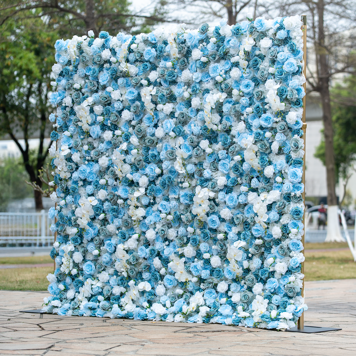 This backdrop is adorned with a dense arrangement of blue and white roses, creating a visually captivating display. The cool - toned flowers exude a serene and elegant charm. Ideal for weddings, galas, or high - end corporate events, it complements themes of sophistication and modern romance. Set outdoors, it adds a touch of natural beauty, making it a stunning focal point for any special occasion. 