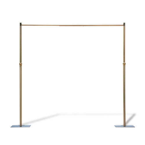 This image features an adjustable - size golden backdrop stand. It consists of two vertical poles connected by a horizontal bar at the top. The vertical poles have adjustable sections, indicated by the presence of connectors, which allow for height modification. The stand is supported by flat, rectangular base plates, providing stability. The golden finish gives it an elegant appearance, making it suitable for events like weddings or photography setups. 