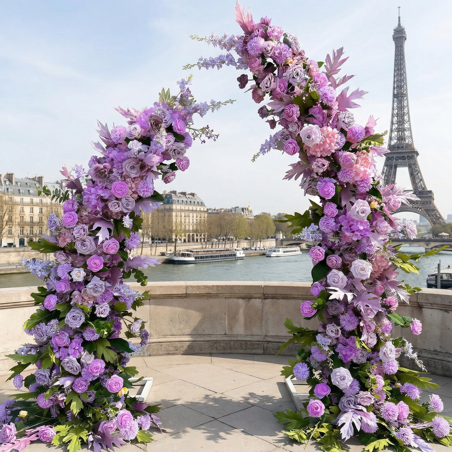 A romantic, asymmetrical floral arch from Valar Flowers, crafted with a dreamy palette of lavender, soft pink, and blush blooms—including roses, peonies, and delicate foliage—intertwined with lush greenery. Set on a sunlit Parisian riverside terrace with the iconic Eiffel Tower in the background, it creates a whimsical, elegant, and sophisticated atmosphere perfect for luxury weddings and editorial photoshoots.