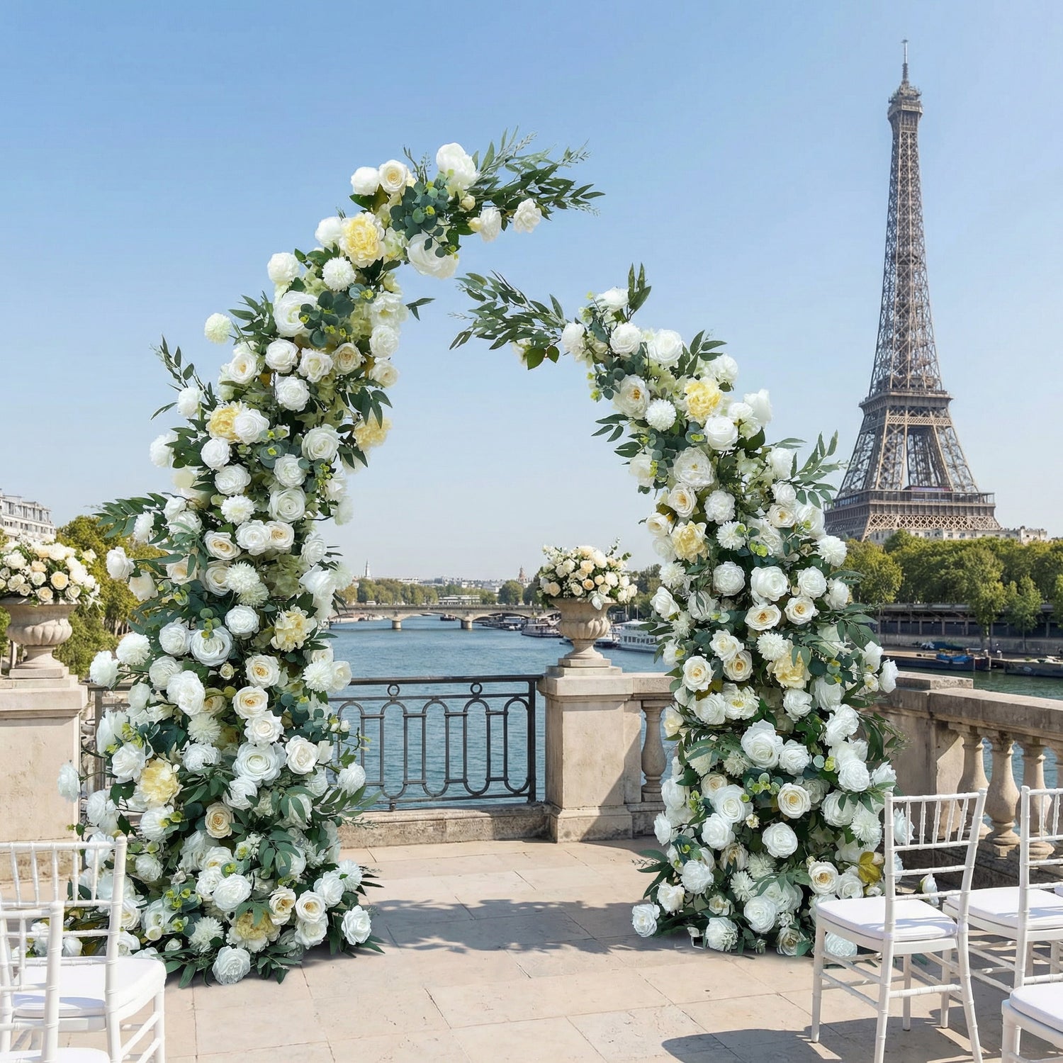 A timeless, asymmetrical floral arch from Valar Flowers, crafted with a fresh palette of pure white and soft cream blooms—including roses, peonies, and delicate foliage—intertwined with lush greenery. Set on a sunlit Parisian riverside terrace with the iconic Eiffel Tower in the background, it creates a serene, elegant, and ethereal atmosphere perfect for luxury weddings and refined photoshoots.