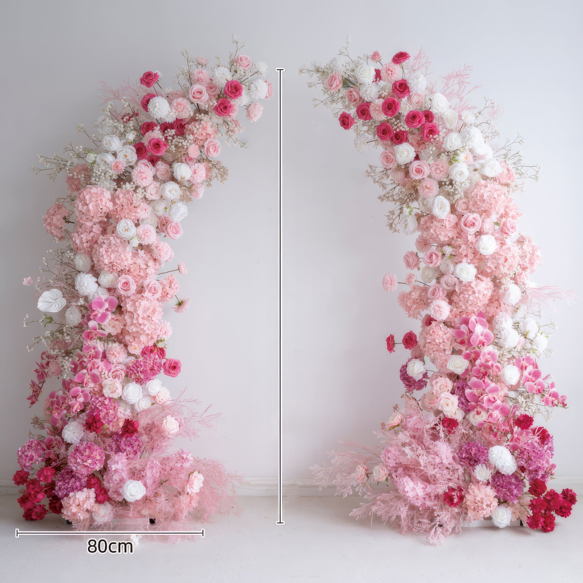 This elegant, symmetrical floral arch, with each side measuring 80cm wide, is adorned with a lush gradient of blush pink, deep rose, and white blooms, including hydrangeas, roses, and delicate filler flowers. The arrangement creates a dreamy, three-dimensional texture, and is set against a minimalist white backdrop. It exudes timeless romance, making it the perfect focal point for weddings, engagement photoshoots, or romantic celebrations.