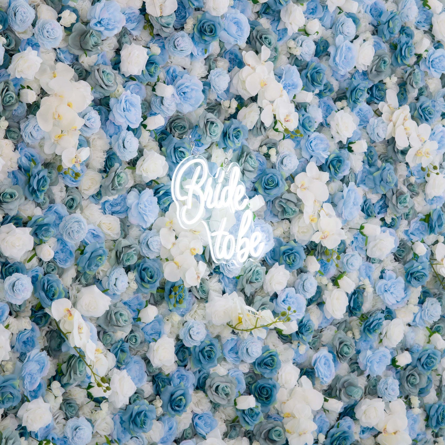 This photo features a lush floral backdrop composed of blue and white roses, interspersed with white orchids. The dense arrangement creates a soft, dreamy effect. At the center, a neon sign reads "Bride to be" in a stylish, glowing font, adding a celebratory touch. Ideal for bridal showers or wedding - related events, the cool - toned flowers and the sign together evoke a romantic and elegant atmosphere. 